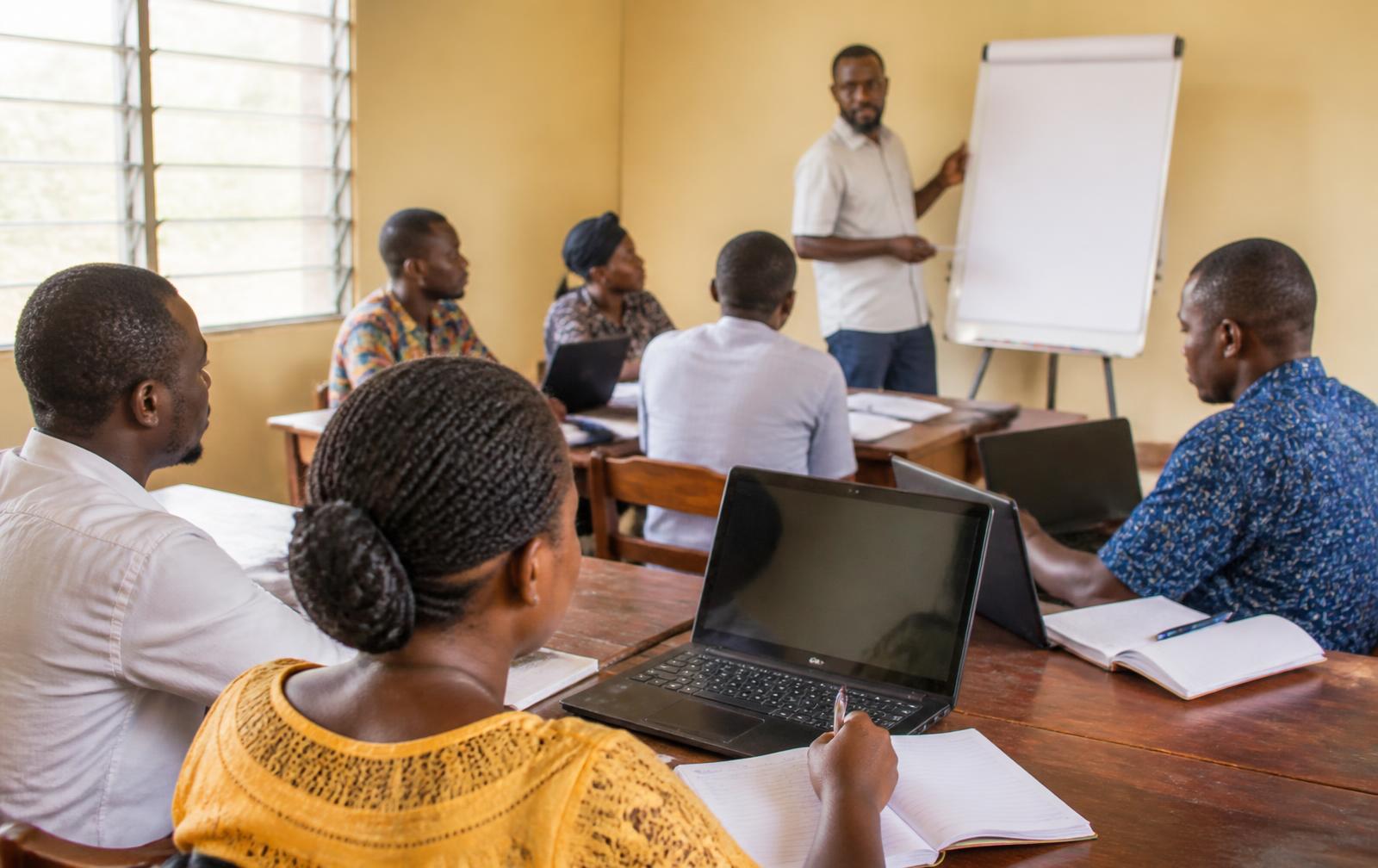 Working adults learning together in a training room in Sierra Leone